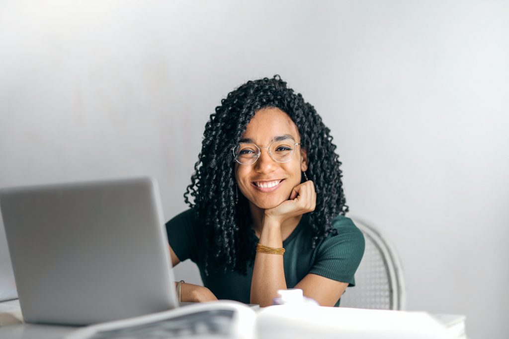 Lächelnde Frau am Schreibtisch vor ihrem Laptop.
